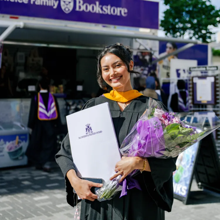 Woman graduating holding flowers 